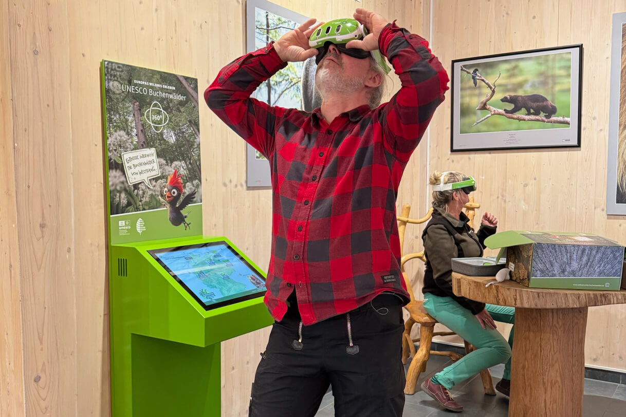 Visitors exploring the beech forests at a national park centre using a VR headset and a touch module