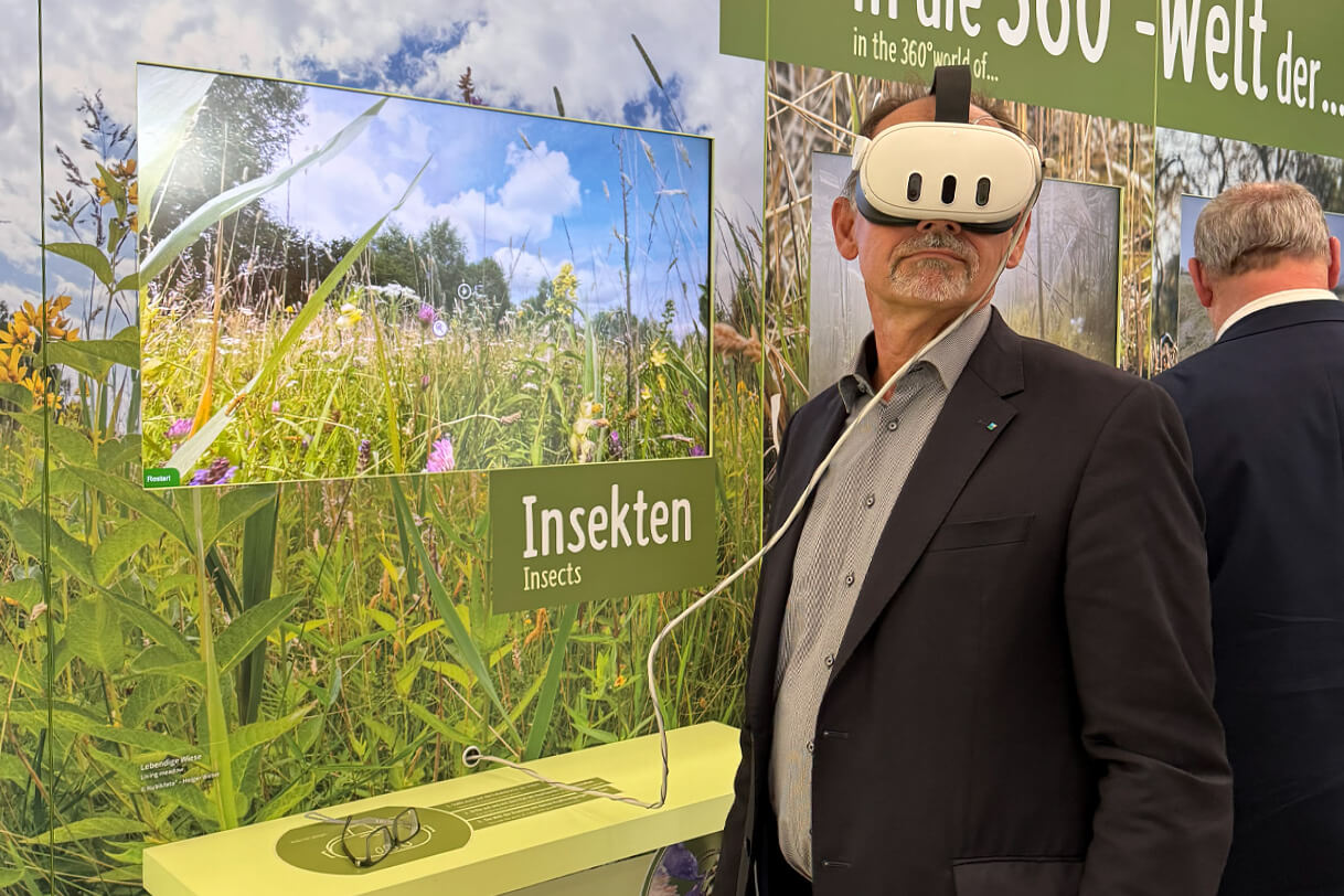 Besucher mit VR-Brille am Insekten-Modul der KRANICHWELTEN, daneben der Touchscreen mit der 360°-Wiesenwelt